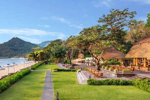 Vana Belle Koh Samui — private beach resort with fine white sand, calm turquoise water and lush tropical garden visible from the water's edge