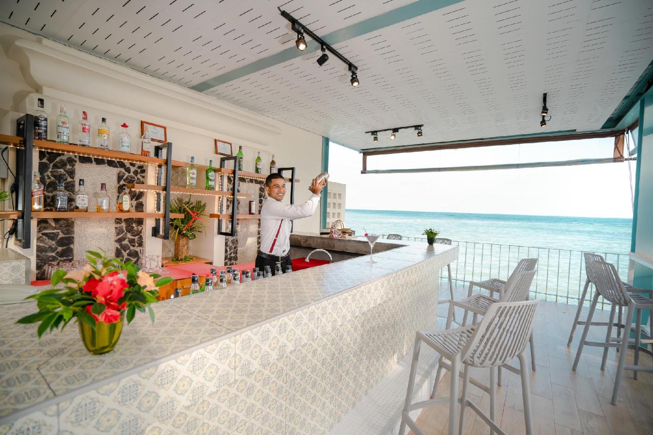 Bar at The Briza Beach Resort, with a curved counter, bottles on the shelves and bar stools