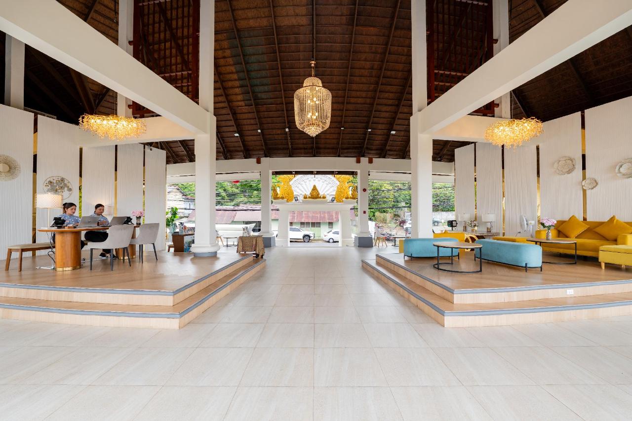 Entrance drive at The Briza Beach Resort, with a thatched-roof building, palms and a stone sign