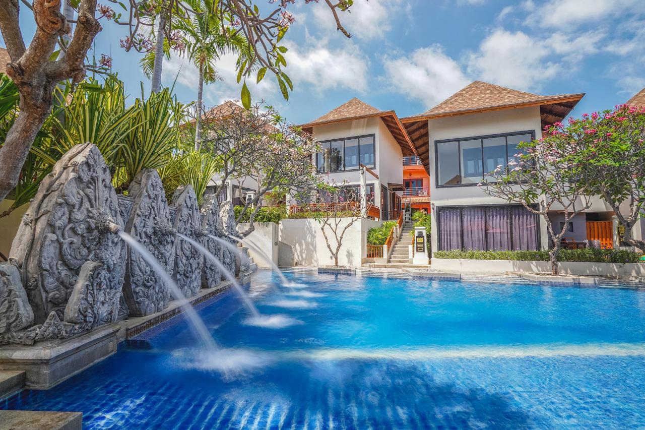 Outdoor swimming pool at The Briza Beach Resort, with blue water, a wooden deck and palm trees
