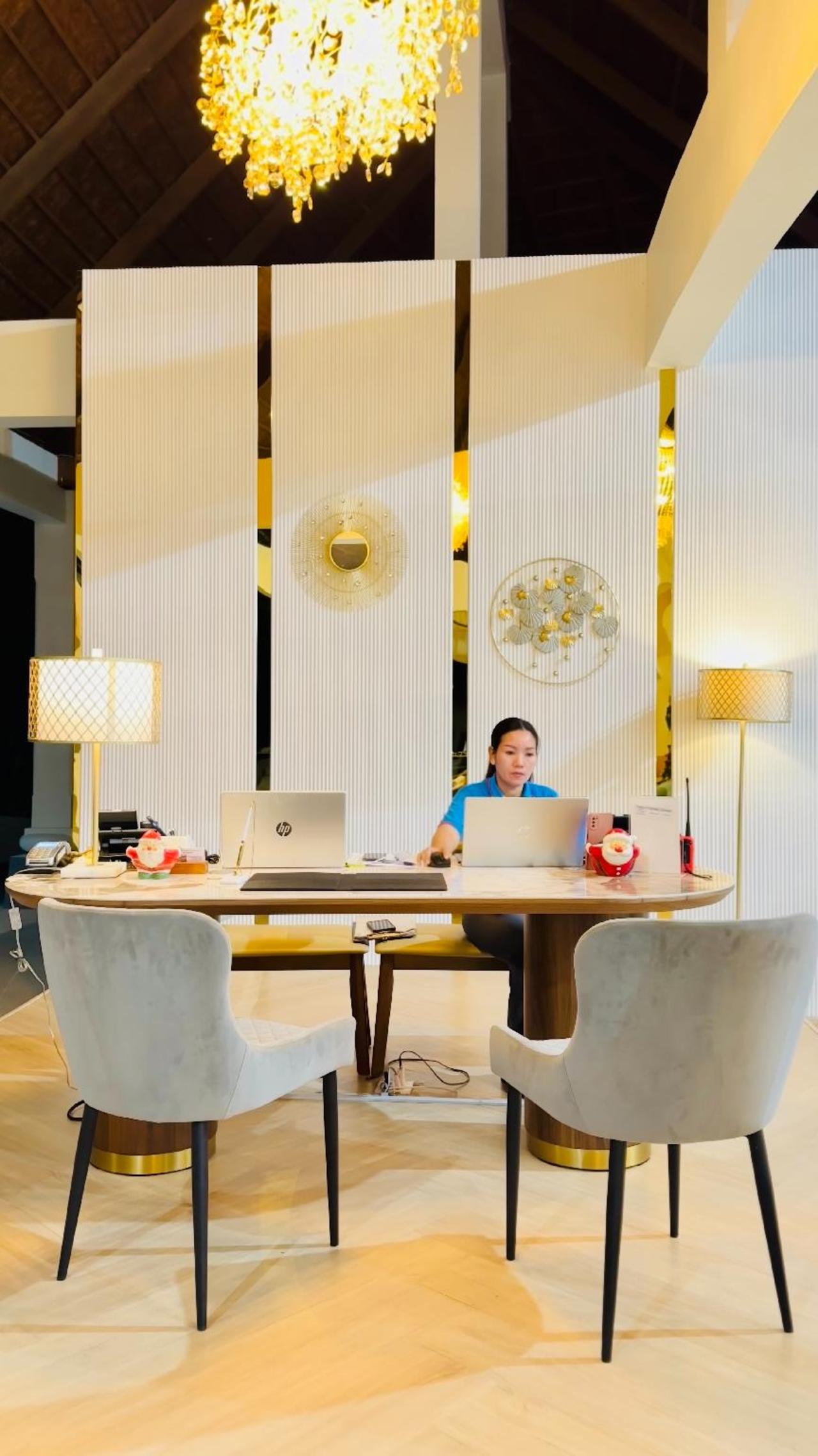 Reception desk at The Briza Beach Resort, with a wooden counter, the BRIZA logo and a tiled floor