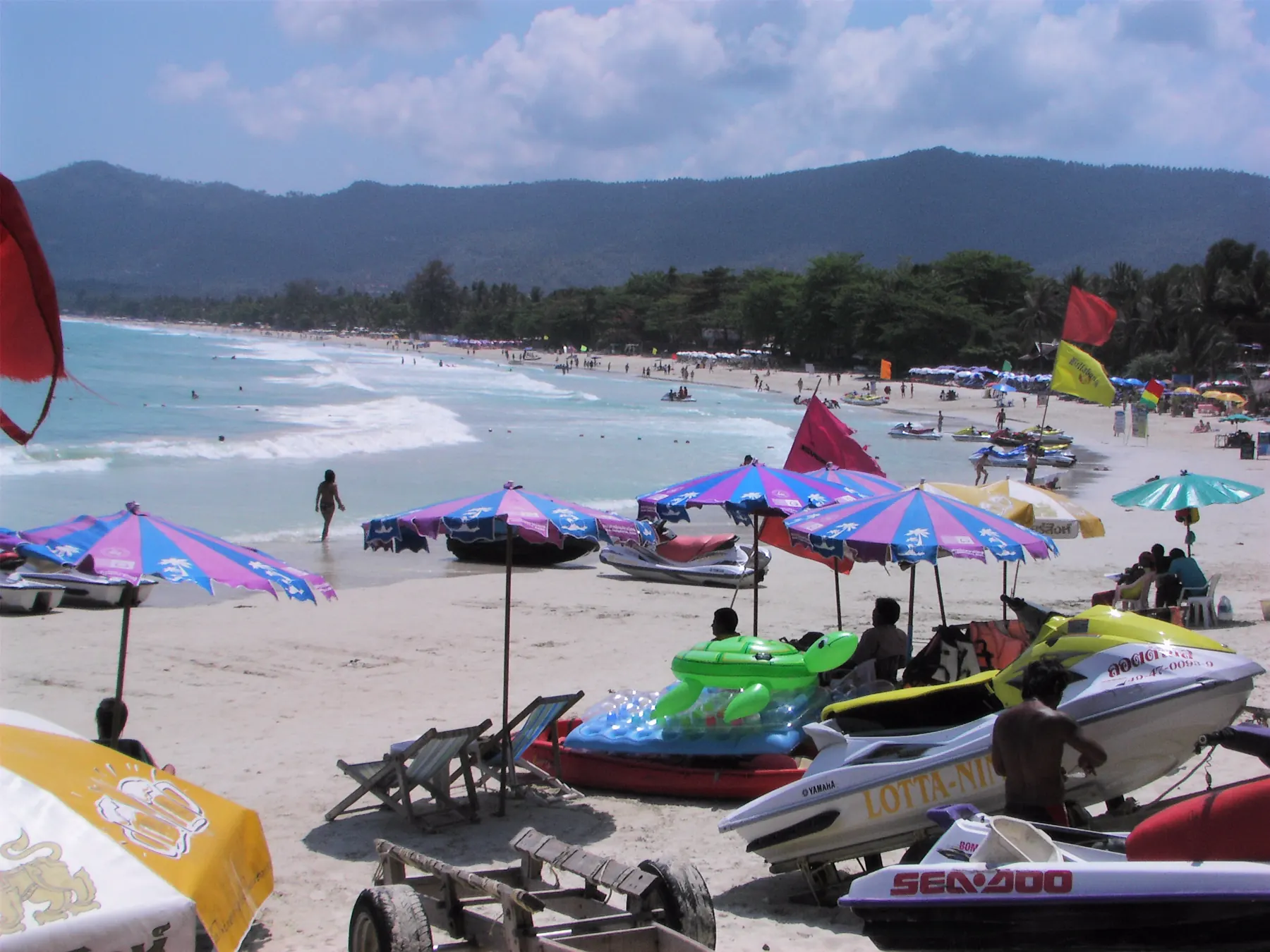 Chaweng Beach, Koh Samui, the long sandy bay with beach umbrellas and green hills behind the shore