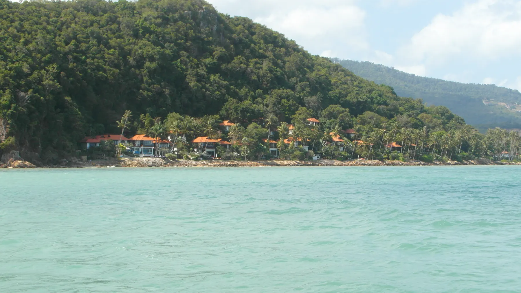 Maenam Beach on the north coast of Koh Samui, a long sandy shore with palms, beach umbrellas and boats offshore